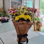 A colorful bouquet of chrysanthemums, baby’s breath and lilies in a flower foam base